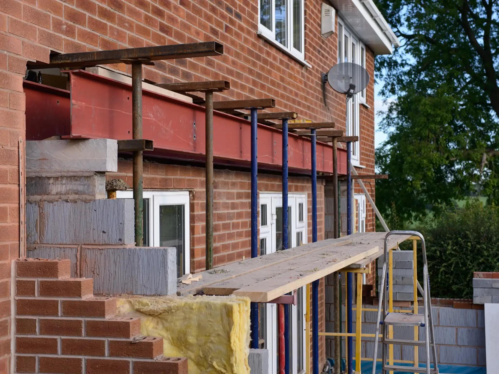 A rear extension under construction with blockwork, timber props and a ladder