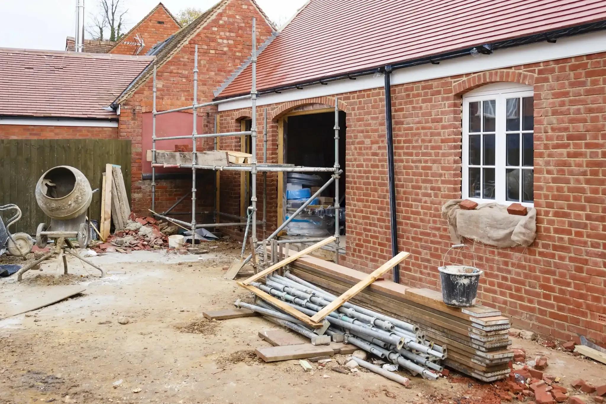 A brick extension under construction with scaffolding and a cement mixer