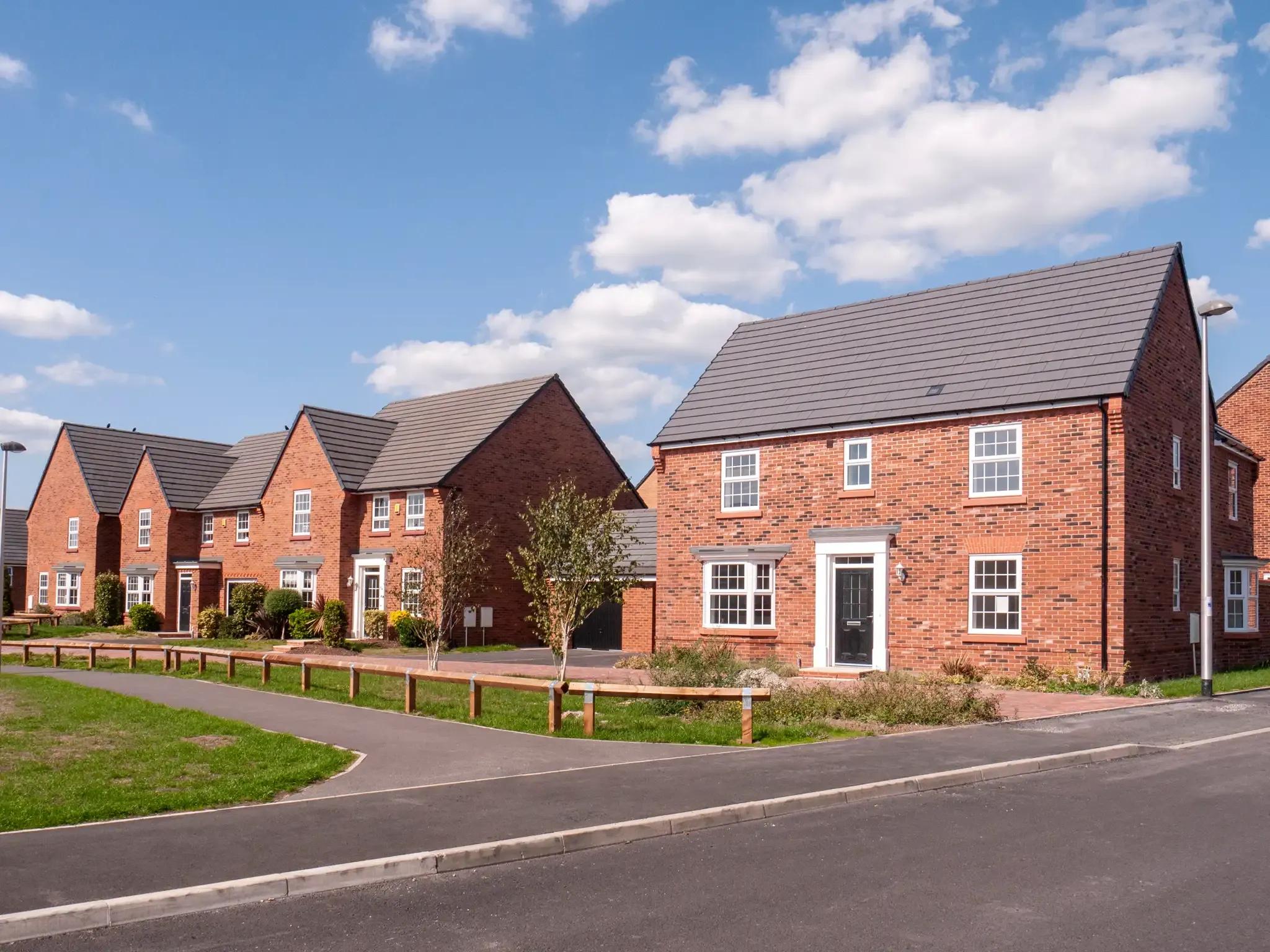 A street of red-brick new-build houses with grass verges