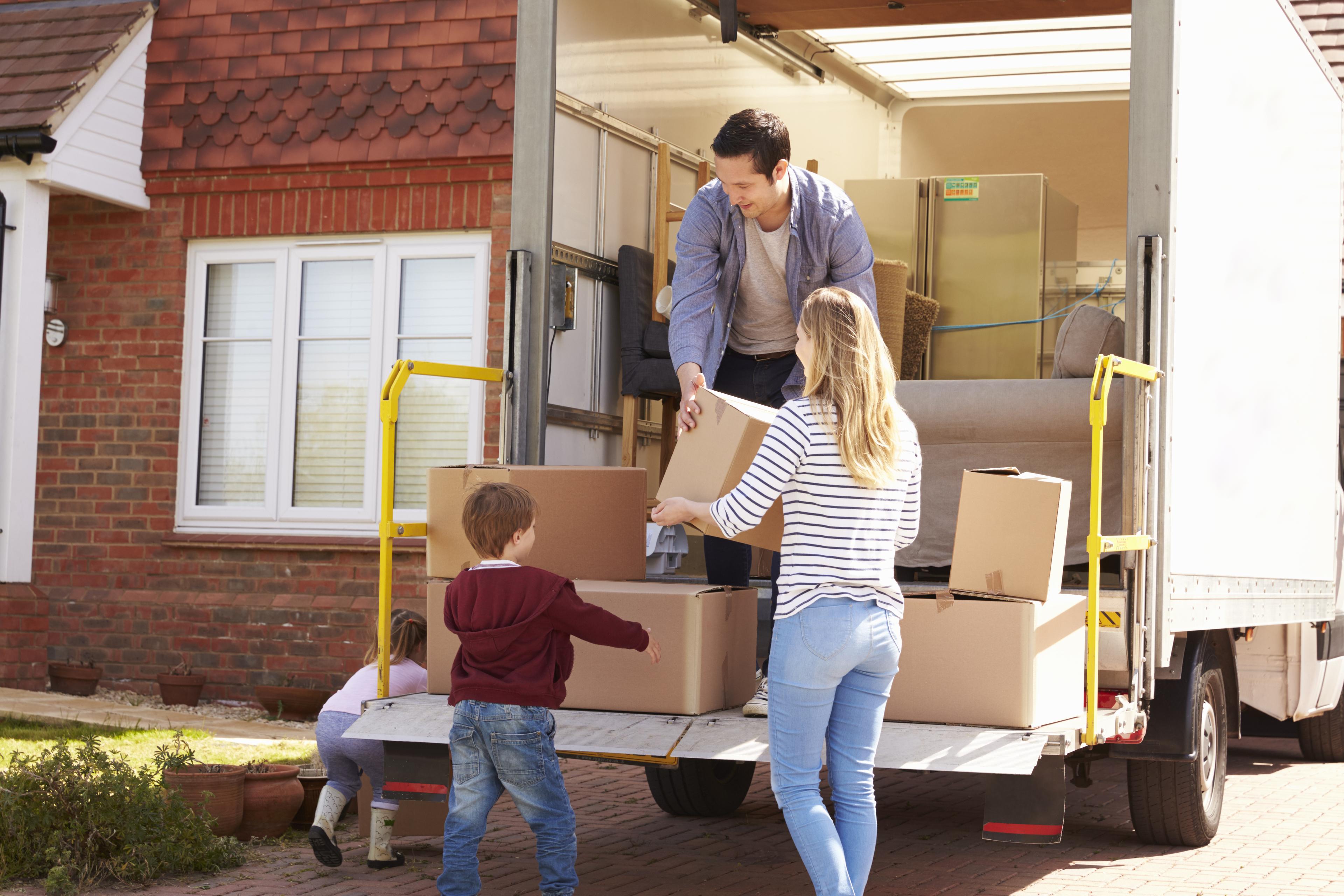 Family,Unpacking,Moving,In,Boxes,From,Removal,Truck