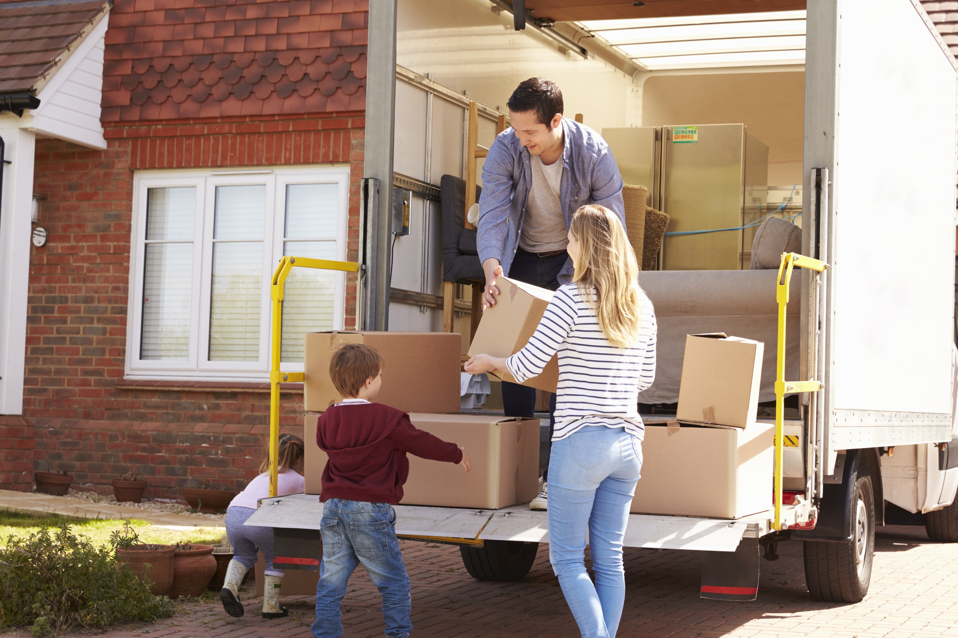 Family,Unpacking,Moving,In,Boxes,From,Removal,Truck